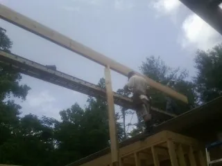 Carpenter setting a ridge beam over a new addition frame — Ice Dam Removal by Roofing Brothers in Lehman