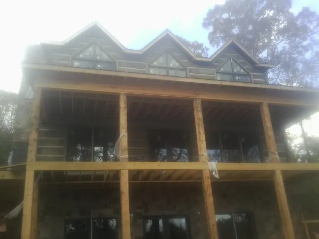Dormers and porch framing on a large log home under construction — Roof Coating work by our crew in Lehman