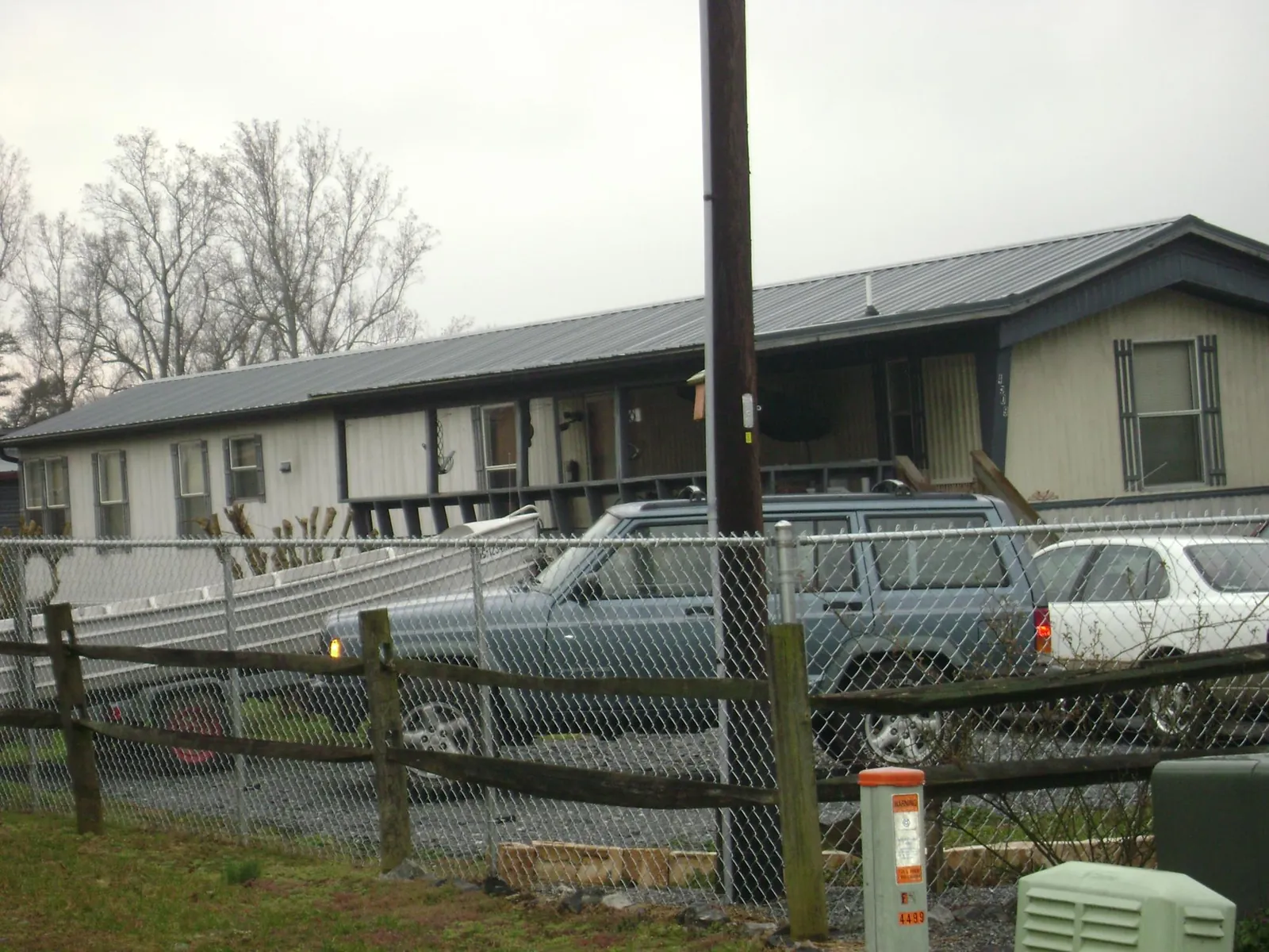 Dark metal roof on a long single story building behind a chain link fence in Lehman