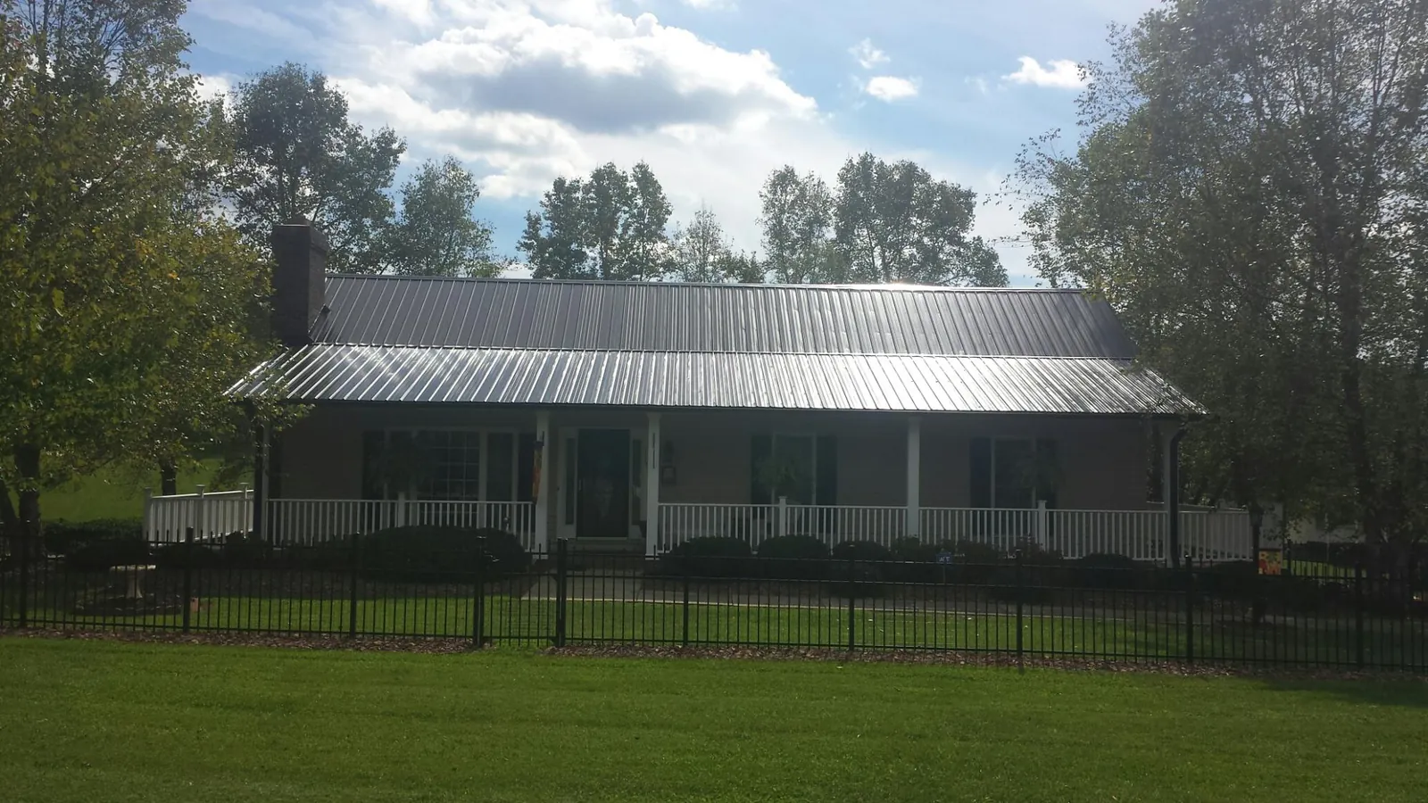 Gray metal roof on a brick ranch with a full width front porch — Gutter Guard Installation work by our crew in Lehman