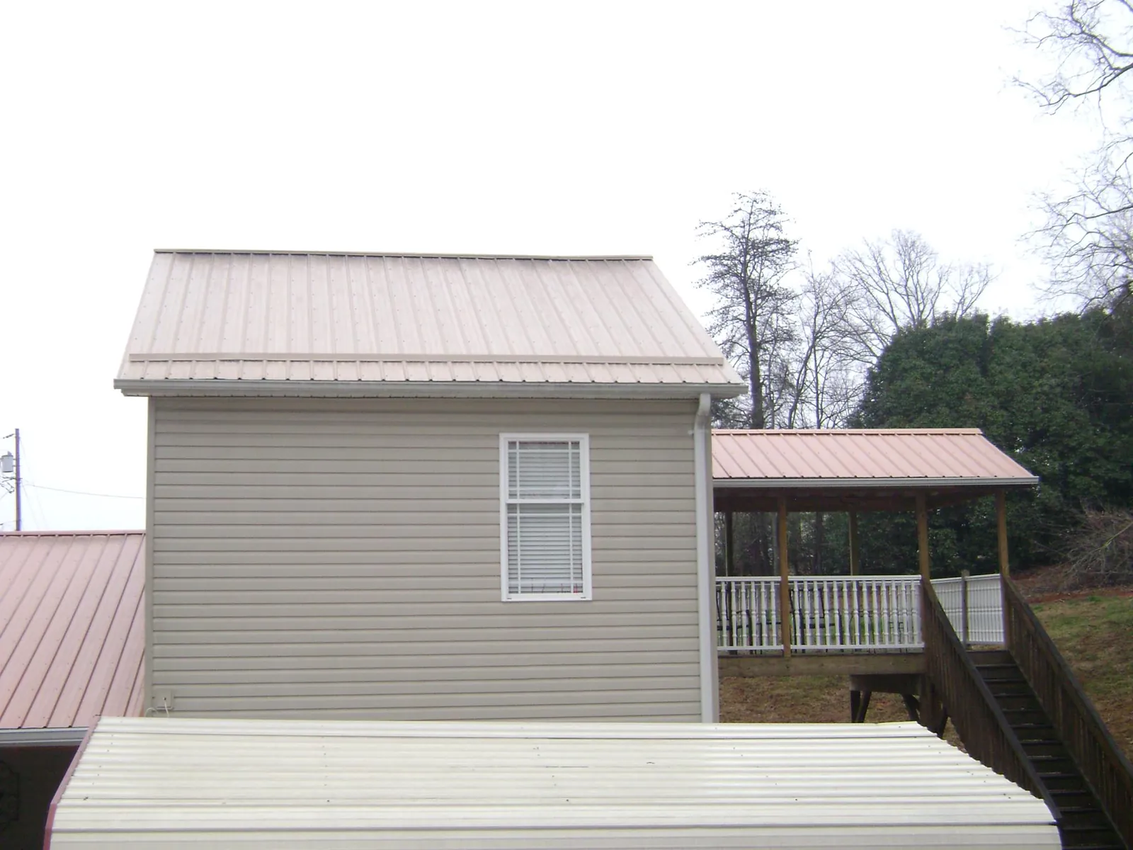 Tan metal roofs on a two story addition and attached porch, from a Roof Replacement job in Lehman
