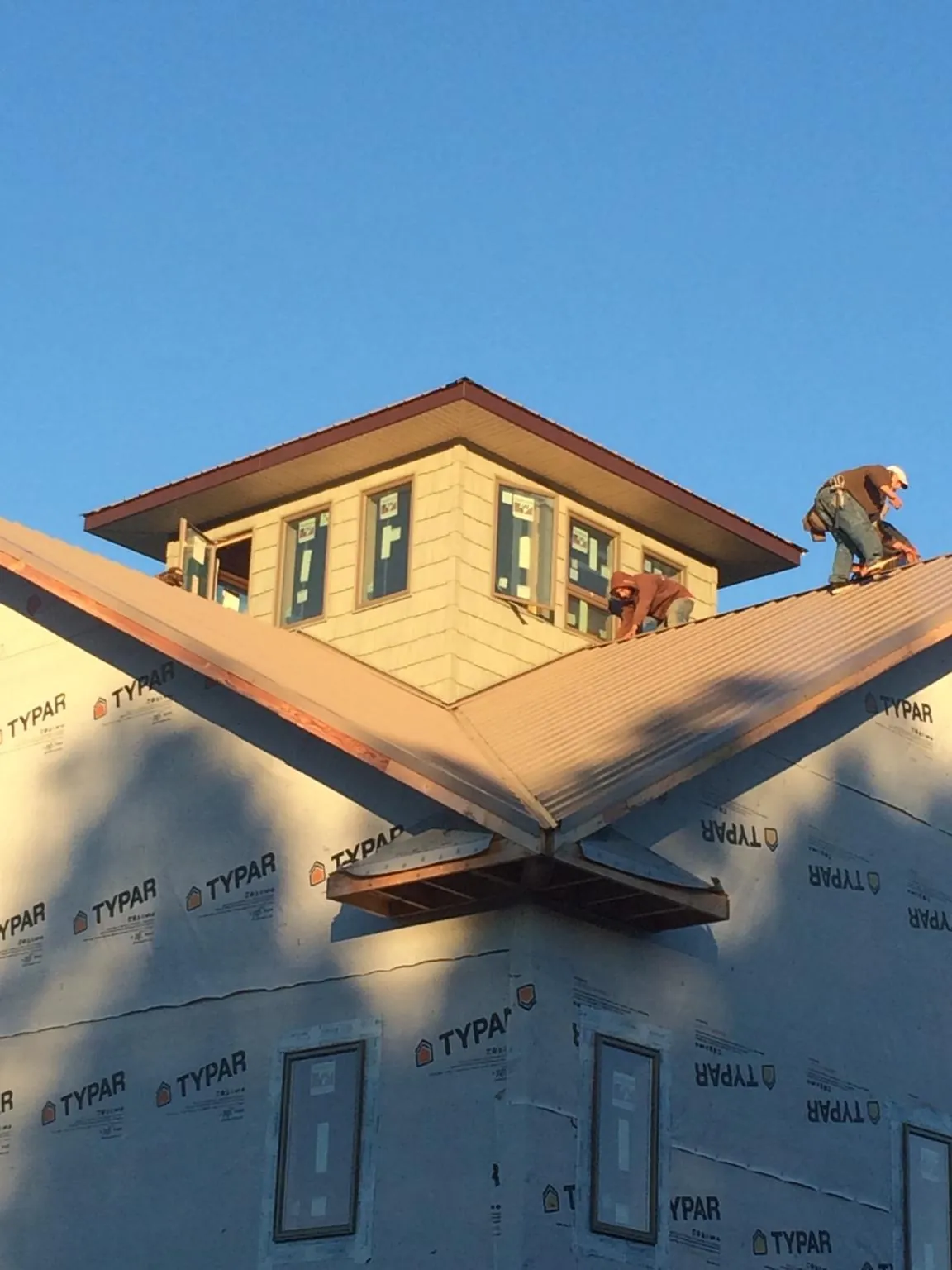 Roofers working around a rooftop cupola on a new metal roof at sunset — Roof Waterproofing in Lehman by Roofing Brothers